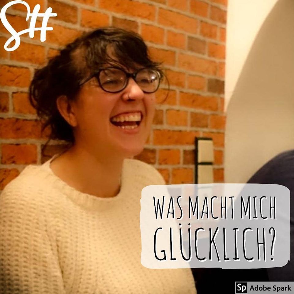 Frau mit Brille in weißem Pullover lacht herzhaft