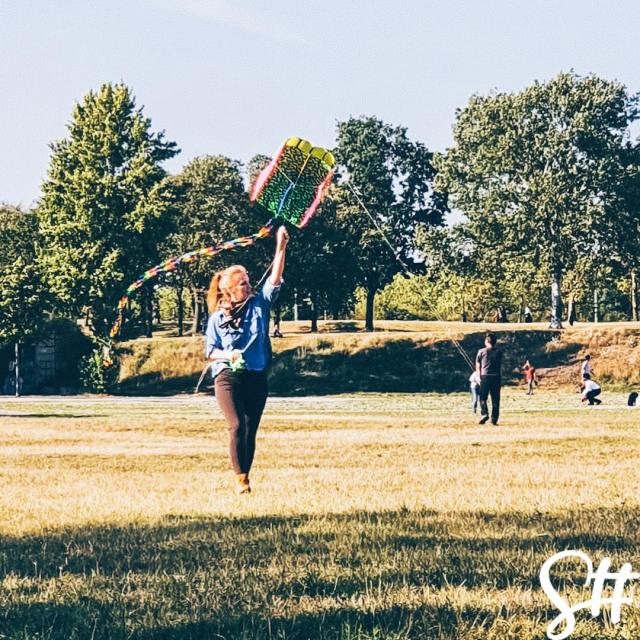 blonde frau auf Feld lässt Drachensteigen